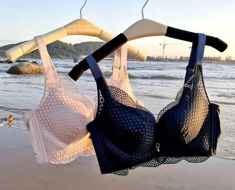 Two seamless lace push-up bras—one in black and the other in beige—hanging on display near the shoreline, highlighting their breathable fabric and elegant scalloped edges.